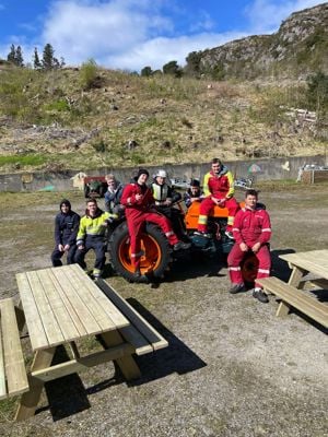 Elevar som sit på ein traktor, med benkar framfor seg.