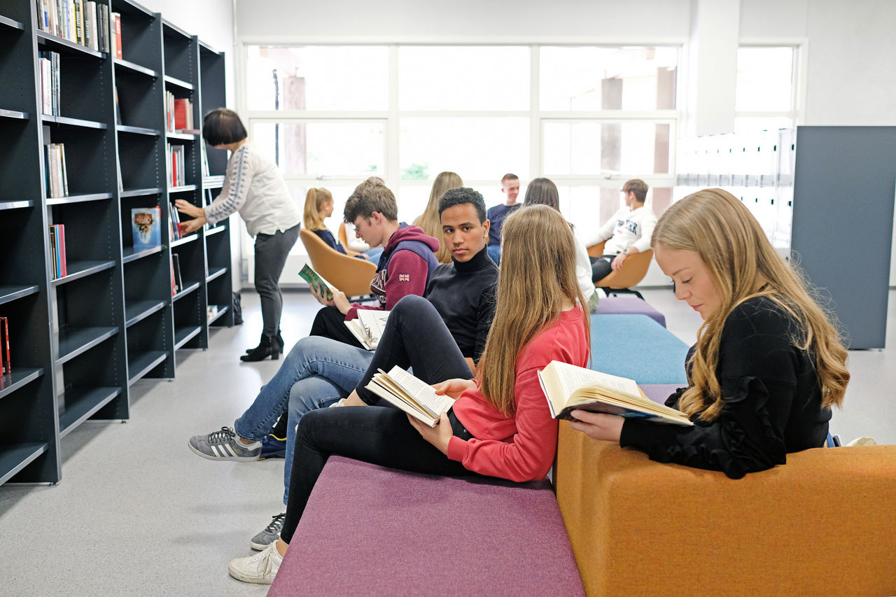 Fleire elevar som sit på biblioteket og les bøker