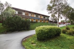 Framsida av skulen sitt hovudbygg. Det står "Måløy vidaregåande skule" med blå bokstavar på veggen.