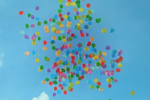 Hundrevis av fargerike ballonger som flyr mot ein blå knall himmel.